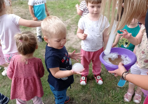 Jasio trzyma magiczną bańkę mydlaną z zawartym w niej dymkiem. Wokół są obserwujące dzieci.